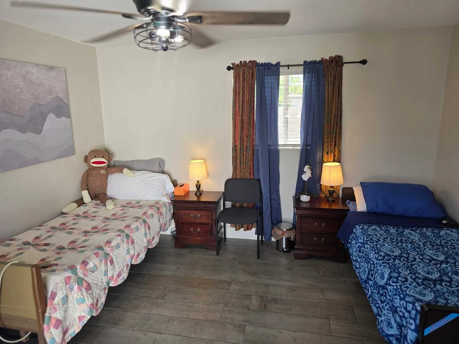A shared bedroom at Latham where one bed is covered with a hand-stitched quilt and a resident’s stuffed toy sits against the pillow