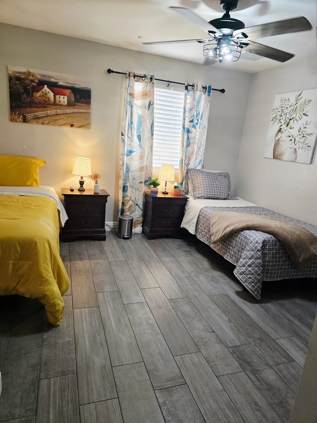 A shared bedroom at Latham with two twin beds made up in yellow and gray, lit by a window between them